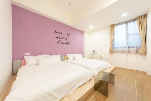 2 Betten in einem Schlafzimmer mit einer lila Wand in der Unterkunft 暖日民宿 in Xingjian