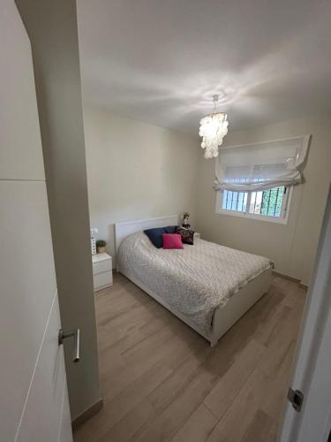 une chambre avec un lit, une fenêtre et un lustre dans l'établissement LA CASA DE LOS PATOS Jardines del lago, à Costa de Sanlúcar