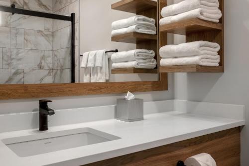 a bathroom with a sink and a mirror and towels at Ramada by Wyndham Cochrane in Cochrane