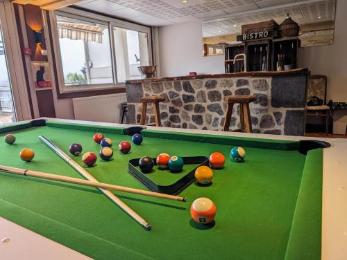 a room with a pool table with balls and bats at Logis Hôtel Le Beau Site in Chambon-sur-Lac