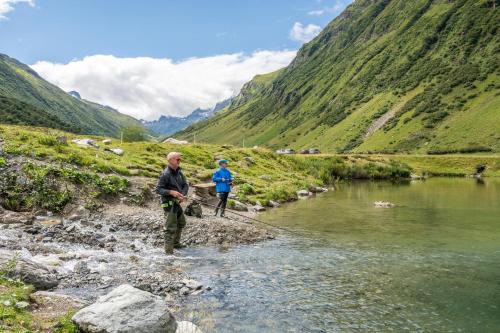 two people standing in a river with a fishing line at Hotel Garni Bel-Ami in Galtür