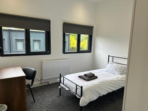 una camera con un letto e una sedia e due finestre di Grace Dieu Manor Park a Thringstone