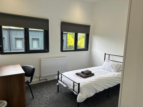 a bedroom with a bed and a chair and two windows at Grace Dieu Manor Park in Thringstone