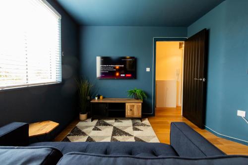 Habitación azul con sofá y TV en la pared en Wigan Gem: Chic 1BR close to CC en Wigan