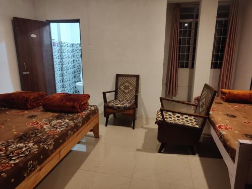 a bedroom with two beds and a chair and a mirror at Breeze Hills Inn in Cherrapunji