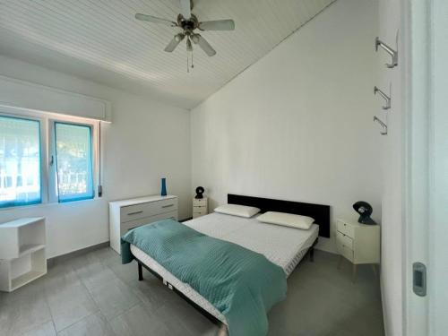 Casa Azzurra في Germignaga: غرفة نوم بيضاء مع سرير ومروحة سقف