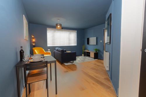 uma sala de estar azul com uma mesa e um sofá em Wigan Gem: Chic 1BR close to CC em Wigan