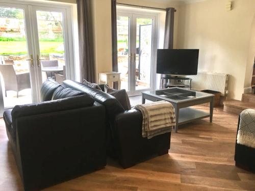 a living room with two leather couches and a television at Stay at The lodge set in the grounds of a beautiful Manor House in Wimborne Minster