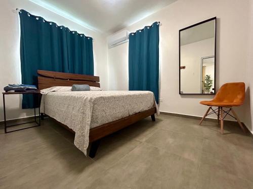 Schlafzimmer mit einem Bett mit blauen Vorhängen und einem Spiegel in der Unterkunft Dorado Beach House in Dorado
