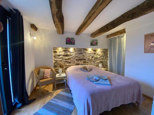 een slaapkamer met een bed en een stenen muur bij Gîte l'Ancienne Forge - La Bouriote in Villefranche-dʼAlbigeois