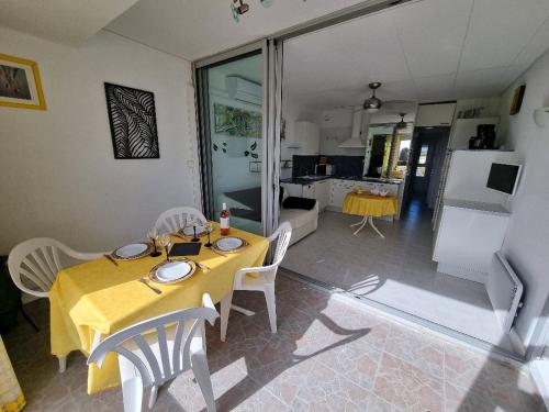 une salle à manger avec une table et des chaises jaunes dans l'établissement Appartement Village Naturiste Psikedelik, au Cap d'Agde