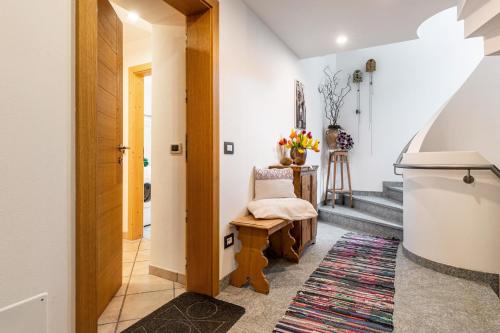 un corridoio con una sedia e scale in una casa di Ciasa Majonade Pozza di Fassa tipo1 a Pozza di Fassa