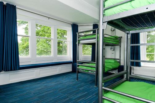 a room with two bunk beds and two windows at YHA Grinton Lodge in Reeth