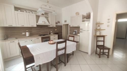 una cucina con armadi bianchi, tavolo e sedie di Da Panco e Vera a Porto Recanati