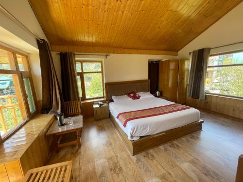 ein Schlafzimmer mit einem großen Bett in einem Zimmer mit Fenstern in der Unterkunft Heavens retreat,Club nirvana stays in Vashisht