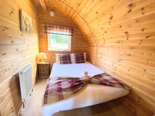 a bedroom with a bed in a wooden cabin at Pond View Pod 1 with Outdoor Hot Tub - Fife - Loch Leven - Lomond Hills in Kelty