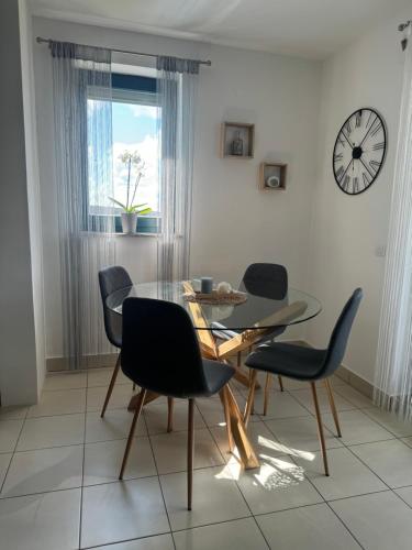 uma sala de jantar com mesa e cadeiras e um relógio em Apartment Mare em Čunski