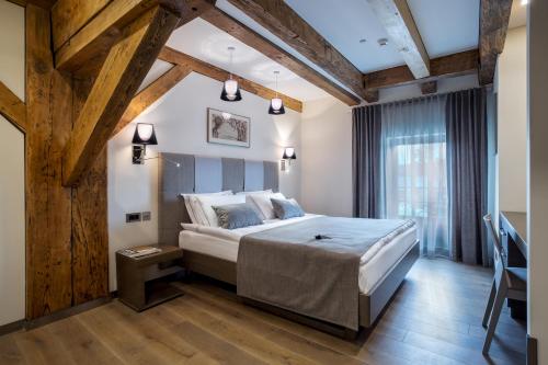 Un dormitorio con una cama grande en una habitación con techos de madera. en Michaelson Boutique Hotel en Klaipėda