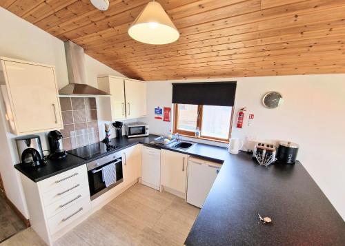 a kitchen with white cabinets and a black counter top at Torridon 12 with Private Hot Tub - Fife - Loch Leven - Lomond Hills in Kelty