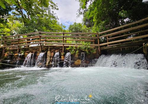 a wooden bridge over a waterfall in a park at Thermas Paradise Residence in Rio Quente