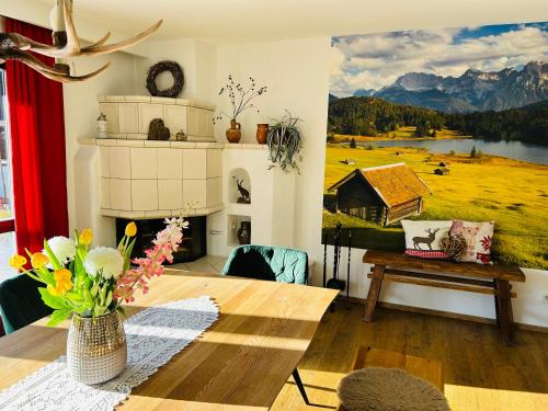 un salon avec une table et une peinture d'une grange dans l'établissement Ferienhaus Alpenperle, à Grainau