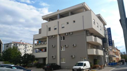 un edificio alto con una furgoneta blanca estacionada frente a él en Hotel Quo Vadis, en Međugorje