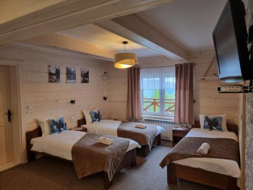 a hotel room with two beds and a television at Schronienie Orłów Domek Zawoja in Zawoja
