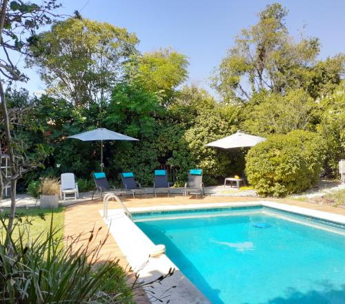 une piscine avec des chaises et des parasols à côté dans l'établissement Villa Serrane - Appartement avec accès piscine, à Carqueiranne