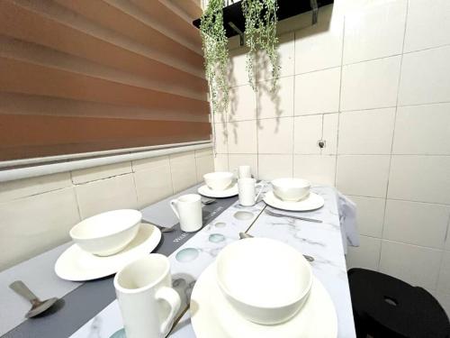 a table with white bowls and plates on it at Cozy 4BR 7Pax MMU Cyberjaya University Tamarind Square in Cyberjaya