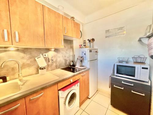 une cuisine avec un évier et un micro-ondes dans l'établissement Le Petit Magellan by Welcome to Cannes, à Cannes