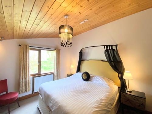 a bedroom with a large bed and a chandelier at Torridon 12 with Private Hot Tub - Fife - Loch Leven - Lomond Hills in Kelty