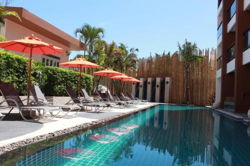 a swimming pool with chairs and umbrellas next to a building at Luxury Suite Room by Atlas X in Kata Beach