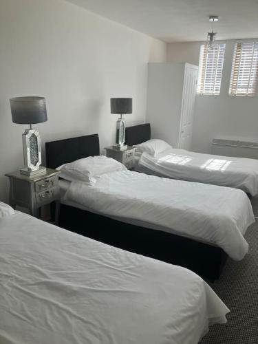 a room with three beds and two tables with lamps at Luna Church Conversion 1 in Blackpool