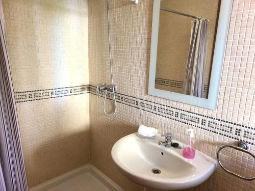 uma casa de banho com um lavatório e um chuveiro com um espelho. em Bungalow Aldea del Mar em Els Poblets