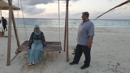 a man and a woman sitting on a swing on the beach at Finimas Residence in Thimarafushi