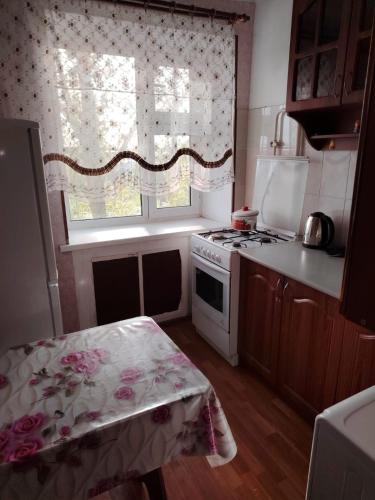 Il comprend une petite cuisine avec une cuisinière et une fenêtre. dans l'établissement 1ком кв центр вокзал, à Uralsk
