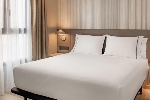 a large white bed with white pillows in a bedroom at AC Hotel by Marriott Clodio Roma in Rome