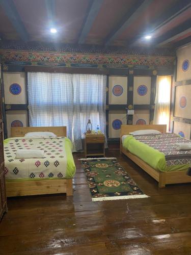 a bedroom with two beds and a rug at Amas Village Lodge in Paro