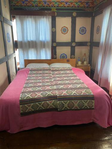 a bedroom with a bed with a colorful blanket on it at Amas Village Lodge in Paro