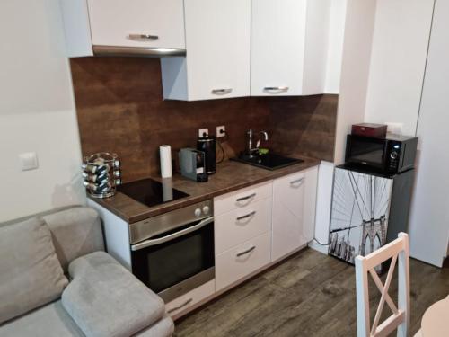 - une petite cuisine avec des placards blancs et un four micro-ondes dans l'établissement Apartman - Centrum, à Bratislava