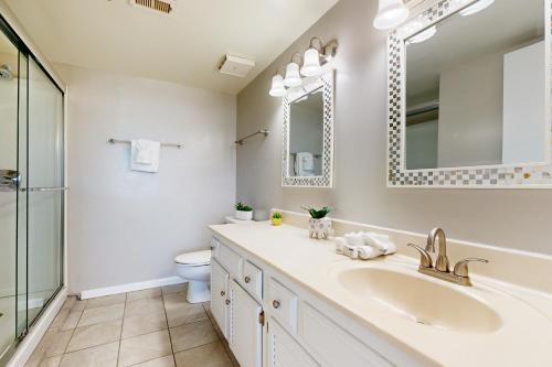 een badkamer met een wastafel, een toilet en een spiegel bij Emerald Surf 102 in Navarre