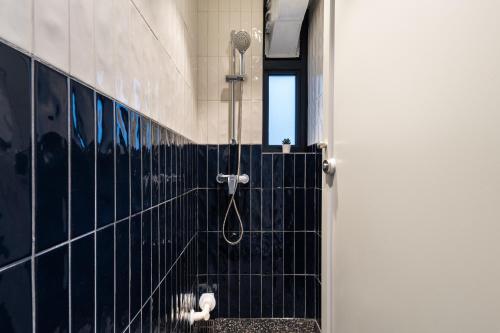 a bathroom with a shower with a black tiled wall at Habyt Bridges - 66 Staunton Street in Hong Kong