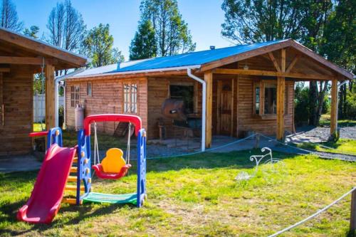 un parque infantil frente a una cabaña de madera en •Cabañas Patagonia•, en Puerto Montt