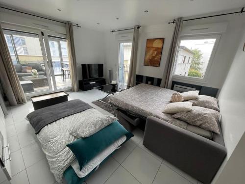 - une grande chambre avec 2 lits et une télévision dans l'établissement Élégant appartement, véranda cosy, à Poissy