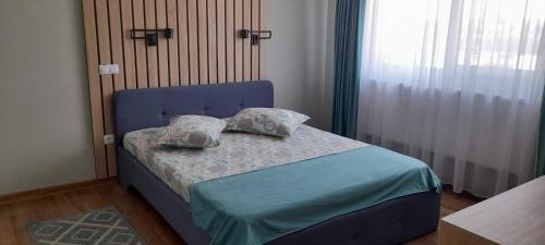 ベクレアンにあるPensiunea Abimarのベッドルーム1室(青いベッド1台、枕付)、窓が備わります。