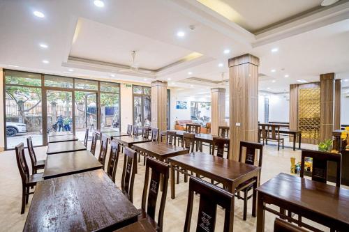 a restaurant with wooden tables and chairs and windows at Sen Vàng Hotel in Sầm Sơn