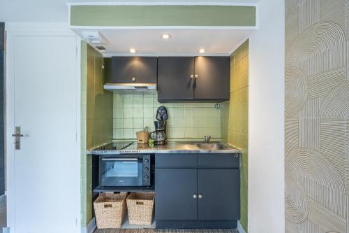 une cuisine avec un évier et un micro-ondes dans l'établissement Studio Hastings GCM, à Grandcamp-Maisy