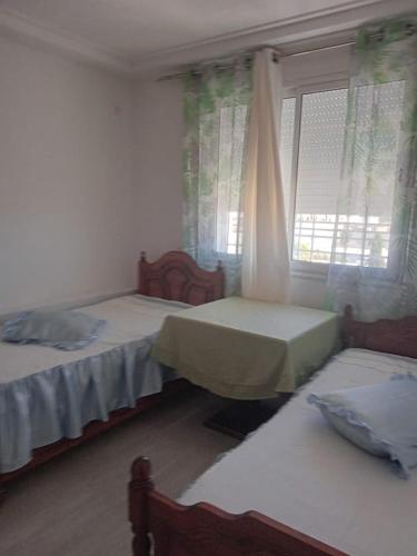 1 dormitorio con 2 camas y una ventana con cortinas en Dar Momo en Nabeul