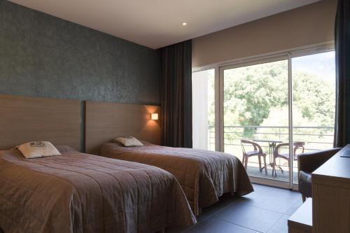 a hotel room with two beds and a balcony at The Originals City, Hôtel de France, Bessines-sur-Gartempe (Inter-Hotel) in Bessines-sur-Gartempe