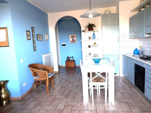 San Savino的住宿－博爾戈聖洛倫薩維諾公寓，厨房拥有蓝色的墙壁和白色的桌椅